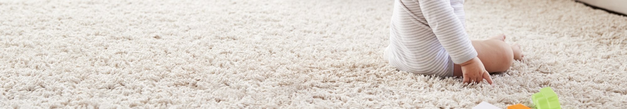A baby sitting on soft, plush carpet flooring